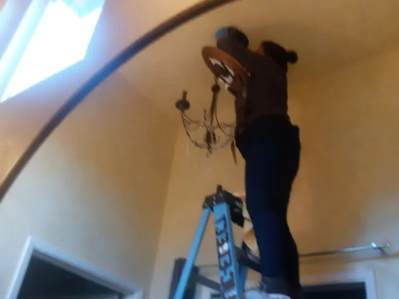 Electrician installing a chandelier in a Chippewa residence